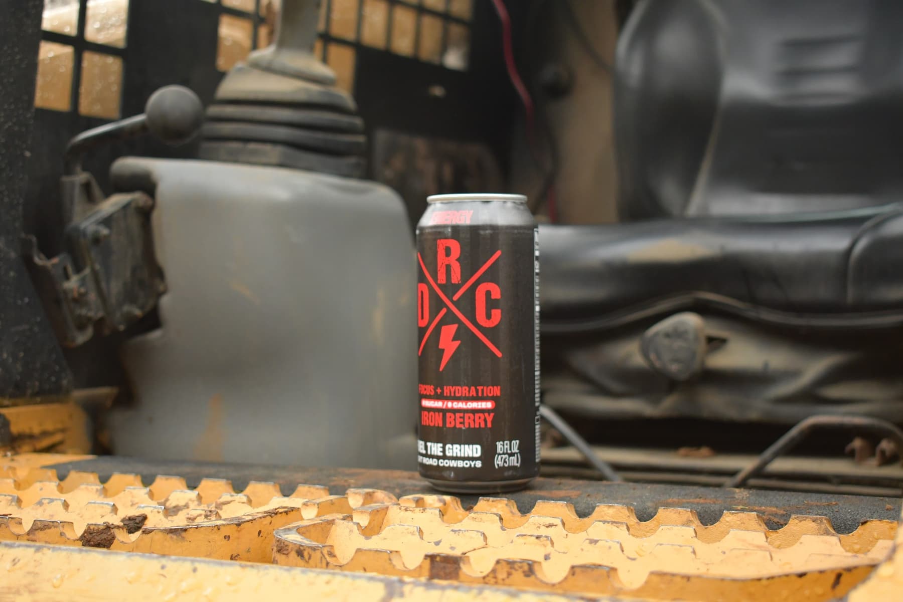 DRC Energy Iron Berry can sitting on the track pad of a skid steer